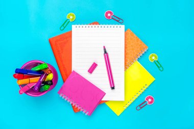 Sabit, okula dönüş, yaz tatili, yaratıcılık ve eğitim kavramı. Malzemeler, makas, kalem, ataç, not ve not defteri, mavi arka plan büyüteç, düz yatak. Üst Görünüm Sancağını Yapılandır.