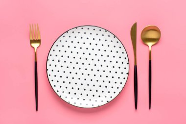 Siyah bezelyeli, çatallı, bıçaklı boş beyaz tabak, modaya uygun pembe arka planda kaşık kahvaltı, öğle yemeği ya da akşam yemeği için düz tabaklar seriliyor..
