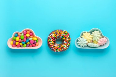 Şekerler - lolipop, kremalar, bulut şeklinde badem kurabiyeleri, çikolatalar, mavi arka planda izole edilmiş renkli çörekler Üst Görüş Knolling Sağlıksız ve lezzetli gıda konsepti.