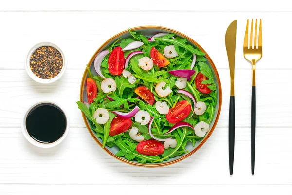 Akdeniz diyet menüsü konsepti taze sebzelerden oluşan sağlıklı salata - domates, roka, mor soğan, karides, soya sosu ve susam tohumları beyaz ahşap masa vegan gıdası düz bir görünüm sergiliyor.