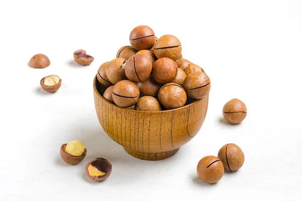 natural organic macadamia nuts in wooden bowl on gray concrete background Flat lay Top view Healthy snack Nuts with essential oil rich in vitamins B, PP, lot of fats and high in calories Superfood