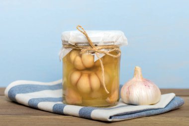 Marinated garlic in closed glass jar and fresh on wooden table Healthy fermented food Homemade pickles. clipart