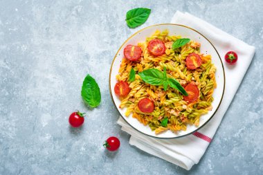 Fusilli - Tavuklu buğday, domatesli kiraz, domates soslu fesleğen, beyaz kâse içinde beyaz beton masa üzerinde Akdeniz mutfağından klasik İtalyan makarnası.