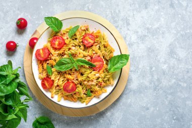 Fusilli - Tavuklu buğday, domatesli kiraz, domates soslu fesleğen, beyaz kâse içinde beyaz beton masa üzerinde Akdeniz mutfağından klasik İtalyan makarnası.