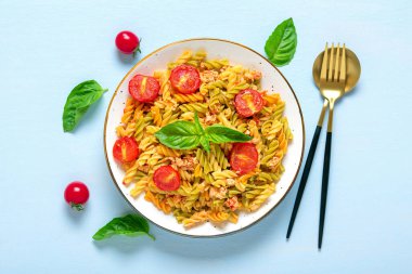 Fusilli - Tavuklu buğday, domates vişneli, fesleğen soslu domates soslu klasik İtalyan makarnası mavi ahşap masada Akdeniz mutfağı.