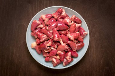 Gri tabakta çiğ tavuk kalbi. Ahşap arka planda izole edilmiş. Düz tabut..