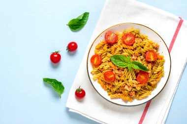 Fusilli - Tavuklu buğday, domates vişneli, fesleğen soslu domates soslu klasik İtalyan makarnası mavi ahşap masada Akdeniz mutfağı