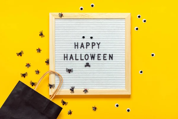 Felt board with text and black package, crawling spiders on yellow background Top view Flat lay Happy Halloween creative concept Holiday card — Stock Photo, Image