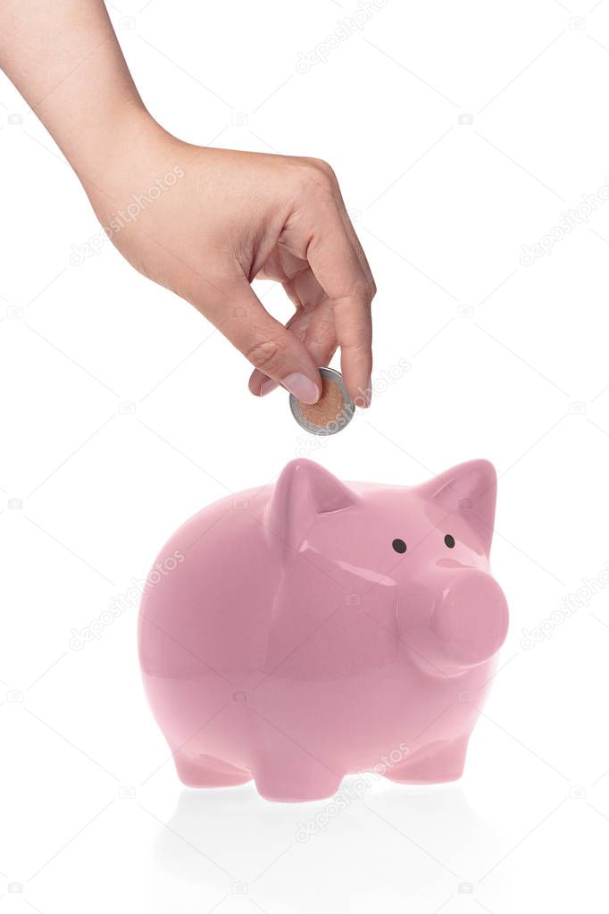 Hand putting coin into piggy bank