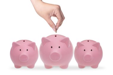 Kumbara para koyarak el. Beyaz zemin üzerinde üç seramik domuzcuk bankalar