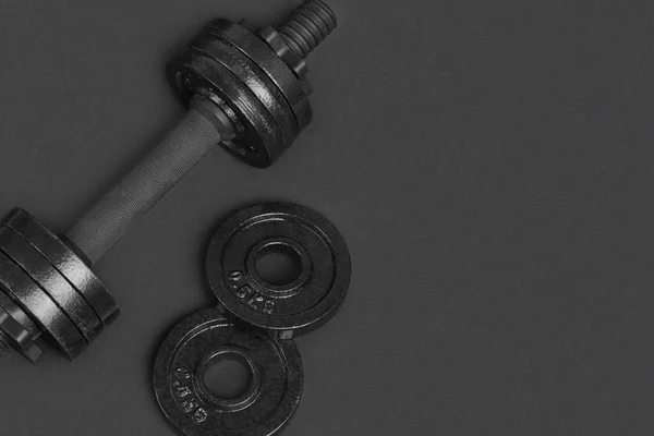 Gri arka planda fitness için siyah metal halter