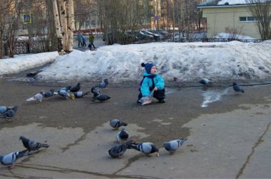 Mavi tulumlu bebek güvercinleri ekmekle besliyor