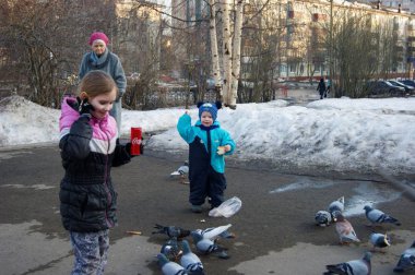 Mavi tulumlu bebek güvercinleri ekmekle besliyor