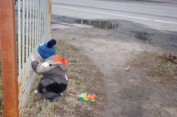 Весна в провінційному місті, маленький хлопчик дійсно хоче дістатися до паркану, за що він не може — стокове фото