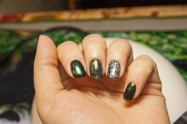 beautiful green manicure, nail polish on nails of different shades of green, with a slight sheen and large shimmer