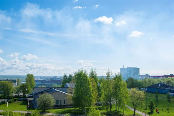 Letní Průmyslová krajina-střechy průmyslových budov proti modrému nebi s bílými mraky — Stock fotografie