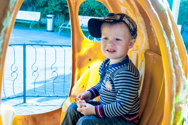 Trzy-letni blond i niebieskooka chłopiec jeździ karuzelą w żółtej dyni. Zabawa, aktywność, wrażenia, emocje. Zimne lato lub wczesna jesień. — Zdjęcie stockowe