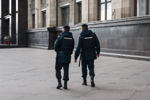 Two policemen walk around the city in the direction from the viewer, we see their backs with the inscription in Russian - translation police — Stock Photo, Image