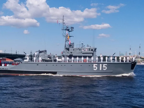 The parade of naval technology. Gray warship with sailors in formal white uniform on board against the background of the bridge — Stock Photo, Image