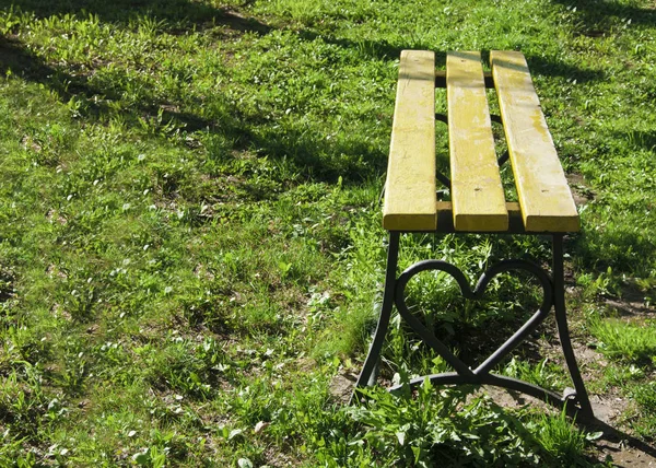 Elementos de la arquitectura del parque urbano: un banco de madera con un corazón forjado para los amantes — Foto de Stock