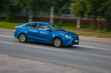 Mavi bir yolcu arabası sakin bir taşra şehrinin caddesinde koşuşturuyor - editör fotoğrafı. Hareket, Görüntü, Defocus