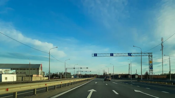 Silnice nebo dálnice vedoucí k horizontu. Pohled z okna auta. Severní šeré léto, modrá obloha s bílými mraky. — Stock fotografie