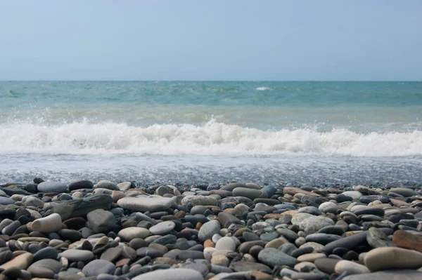 Una pequeña tormenta tres o cuatro puntos en el mar, la ola golpea la orilla con un guijarro grande. — Foto de Stock
