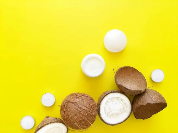 Noix de coco, crème pour le visage ou huile pour le corps sur un fond jaune vif. Concept de soins de la peau, cosmétiques bio naturels, shopping d'été. Vue du dessus, plan, espace de copie pour le texte . — Photo