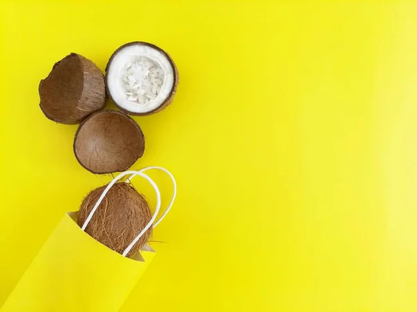 Noix de coco et sac à provisions en papier sur un fond jaune vif. Le concept du shopping d'été et des remises. Vue du dessus, plan, espace de copie pour le texte . — Photo