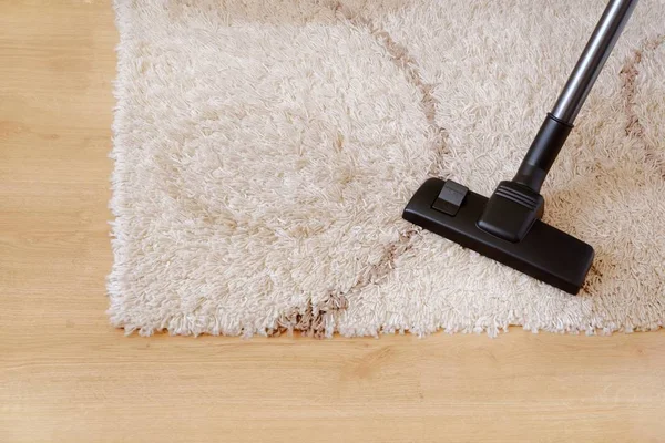 Modern porszívó egy bézs színű szőnyeg fa parketta. A háztartás fogalma, a házimozás, a szőnyeg porszívózása. A szöveg másolása fentről. — Stock Fotó