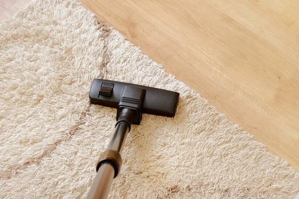 Modern vacuum cleaner on a beige carpet wooden parquet. Concept of housekeeping, housework, vacuuming the carpet. Copy space for text, from above. — Stock Photo, Image