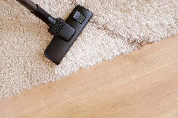 Modern vacuum cleaner on a beige carpet wooden parquet. Concept of housekeeping, housework, vacuuming the carpet. Copy space for text, from above. — Stock Photo, Image