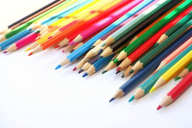 Güneş ışınları beyaz bir arka plan üzerinde yatan renkli kalemler üzerine düşer. Renk Terapisi Kavramı.Seçici odak ile metin için boşluk kopyalamak.