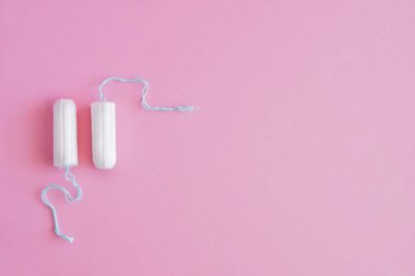 Pembe arka planda iki hijyenik tampon. Menstrüel güve döngüsü, korunma aracı. Üst görünüm, düz döşeme, metin için kopyalama alanı.