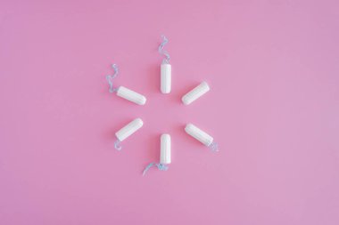 Pembe arka planda birkaç beyaz hijyenik tampon. Menstrüel güve döngüsü, korunma aracı. Üst görünüm, düz döşeme, metin için kopyalama alanı.