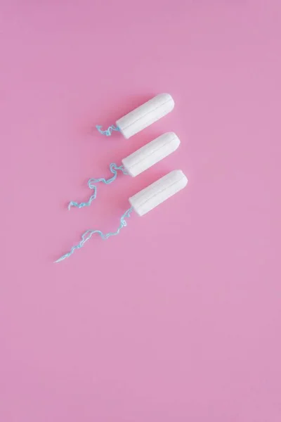 Pembe arka planda üç hijyenik tampon. Menstrüel güve döngüsü, korunma aracı. Üst görünüm, düz döşeme, metin için kopyalama alanı.
