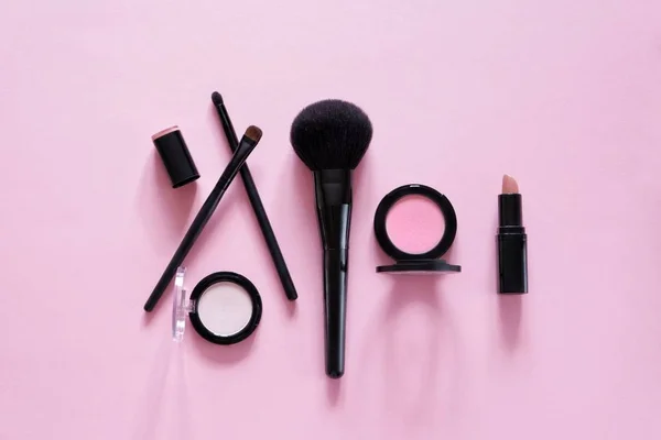 Dekoratif kozmetik, farklı makyaj fırçaları, allık, pembe bir arka plan üzerinde ruj Düz yatıyordu kompozisyon. Üst te. Minimalist yaşam tarzı.