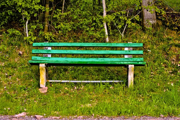 Green old lonely park bench in nature