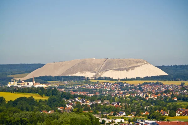 Extracting and mining potassium and magnesium salts.Large excavator machine and Huge mountains of waste ore in the extraction of potassium in the front a small village in Hesse, Germany — Stock Photo, Image