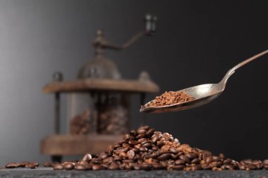 Kahve öğütücüsünün içinde kahve çekirdeklerinin yanında, taştan bir masanın üstünde. Kahve dolduran bir kaşık.