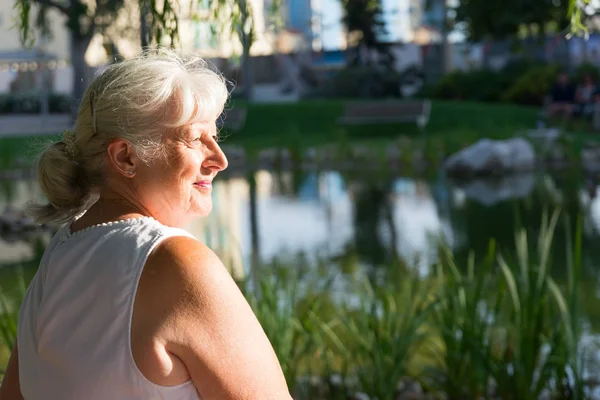 Portrait of the profile of a woman with grey hair smiling with closed mouth