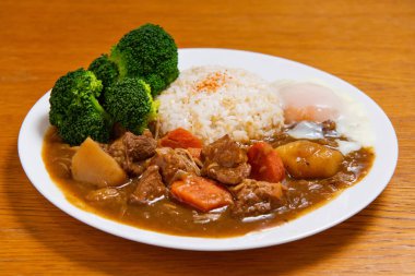 Ahşap zemin üzerinde körili domuz pirinci (Onsen tamago, patates, enoki mantarı, soğan, brokoli, Japon tarzı,)