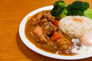 Ahşap zemin üzerinde körili domuz pirinci (Onsen tamago, patates, enoki mantarı, soğan, brokoli, Japon tarzı,)