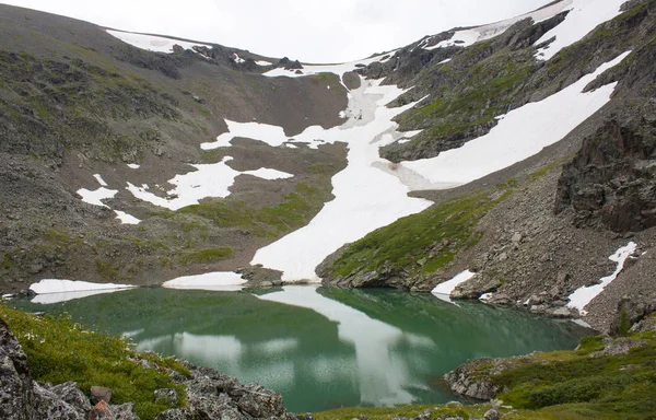 Um lago de montanha de cor turquesa, neve e gelo na costa — Fotografia de Stock