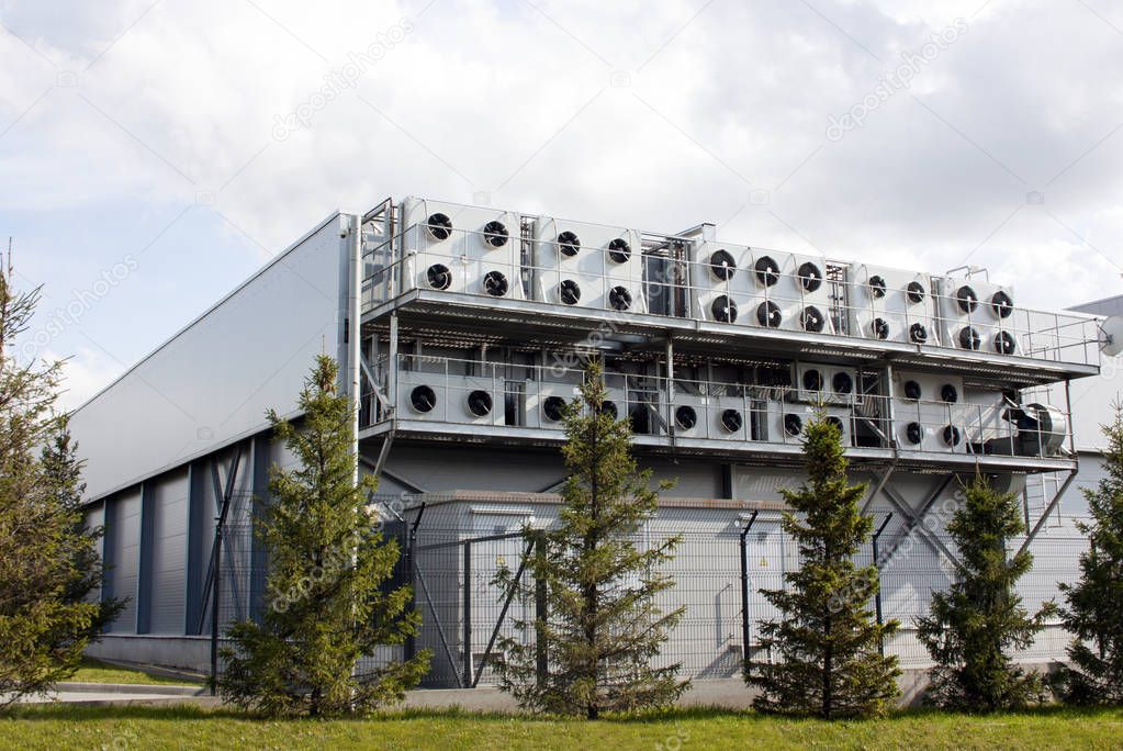 Factory building with lots of air conditioning. Green spruce