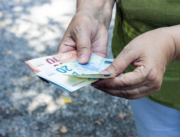 Euro banknotes in the hands. Adult woman counts money