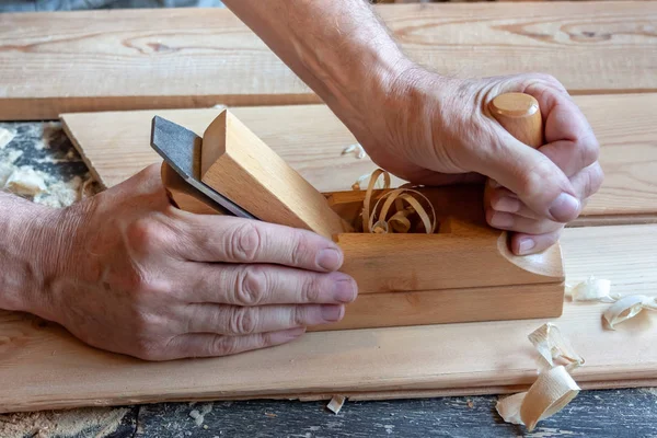 As mãos dos homens seguram um jointer de madeira close-up. Painéis de madeira clara — Fotografia de Stock