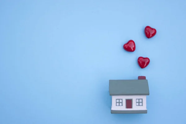 Маленький будинок, три серця вилітають з труби на синьому — стокове фото