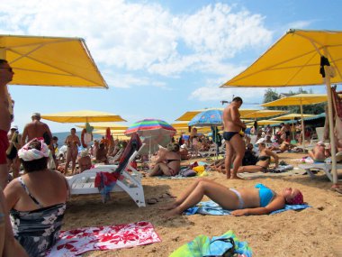 Kırım, Feodosia, 22 Temmuz 2012. Şehir plajı, insanlar güneşleniyor, deniz kenarındaki kumsalda şemsiyelerin altında dinleniyorlar.                               