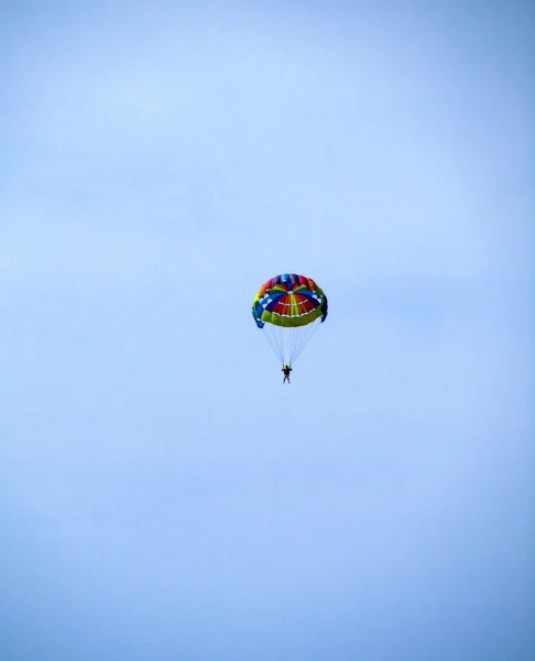 一个带着彩色圆形降落伞的跳伞运动员在蓝天上飞行 垂直照片 — 图库照片